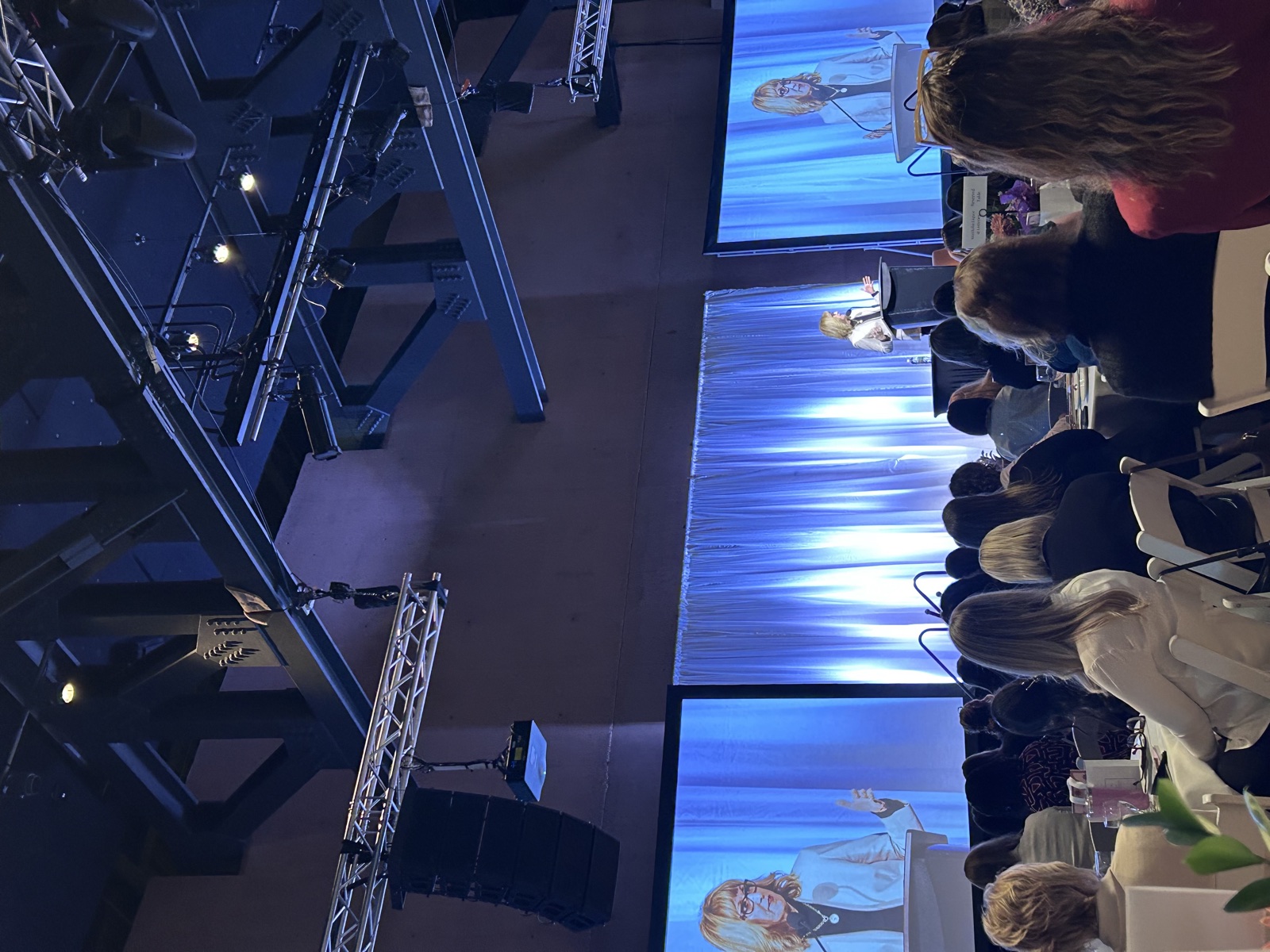 Esther Findlay on stage at a women’s event, shown on the room’s screens.